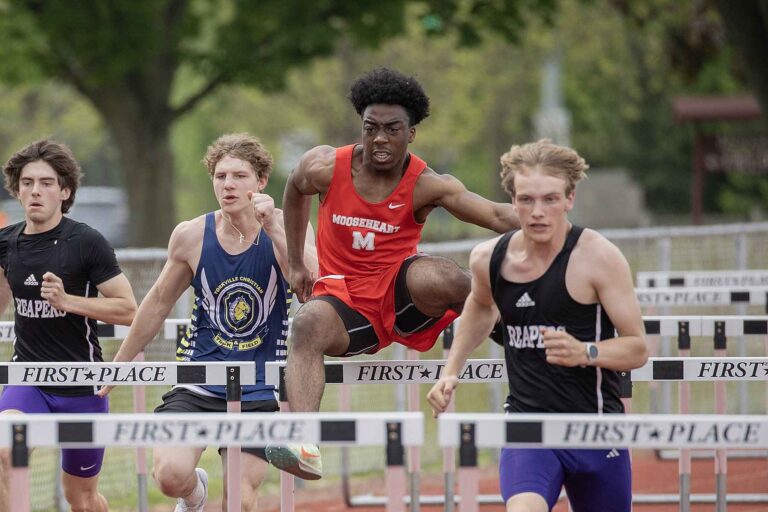 A group of young men competing in a hurdle race, focused and determined as they leap over the obstacles.