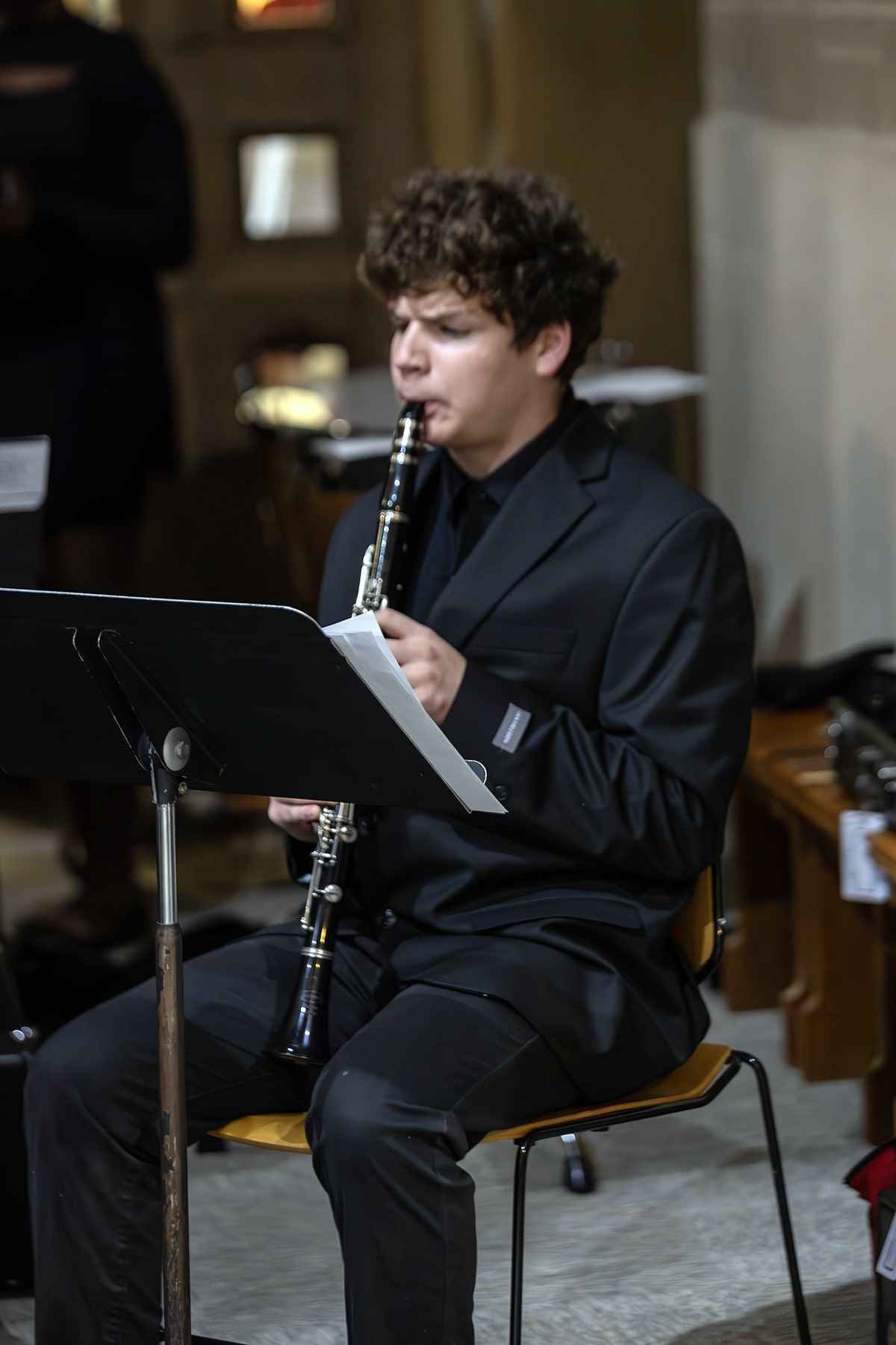A man in a suit playing a clarinet, showcasing his musical talent in a formal setting