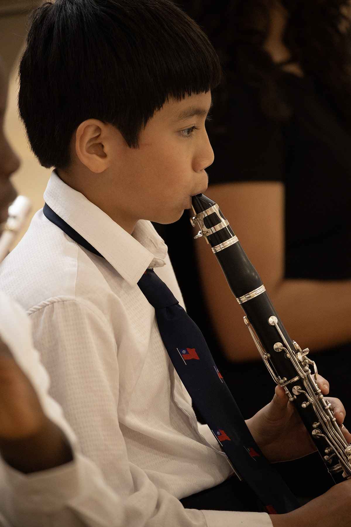 A young boy joyfully playing a clarinet, focused on his music in a bright, cheerful setting.