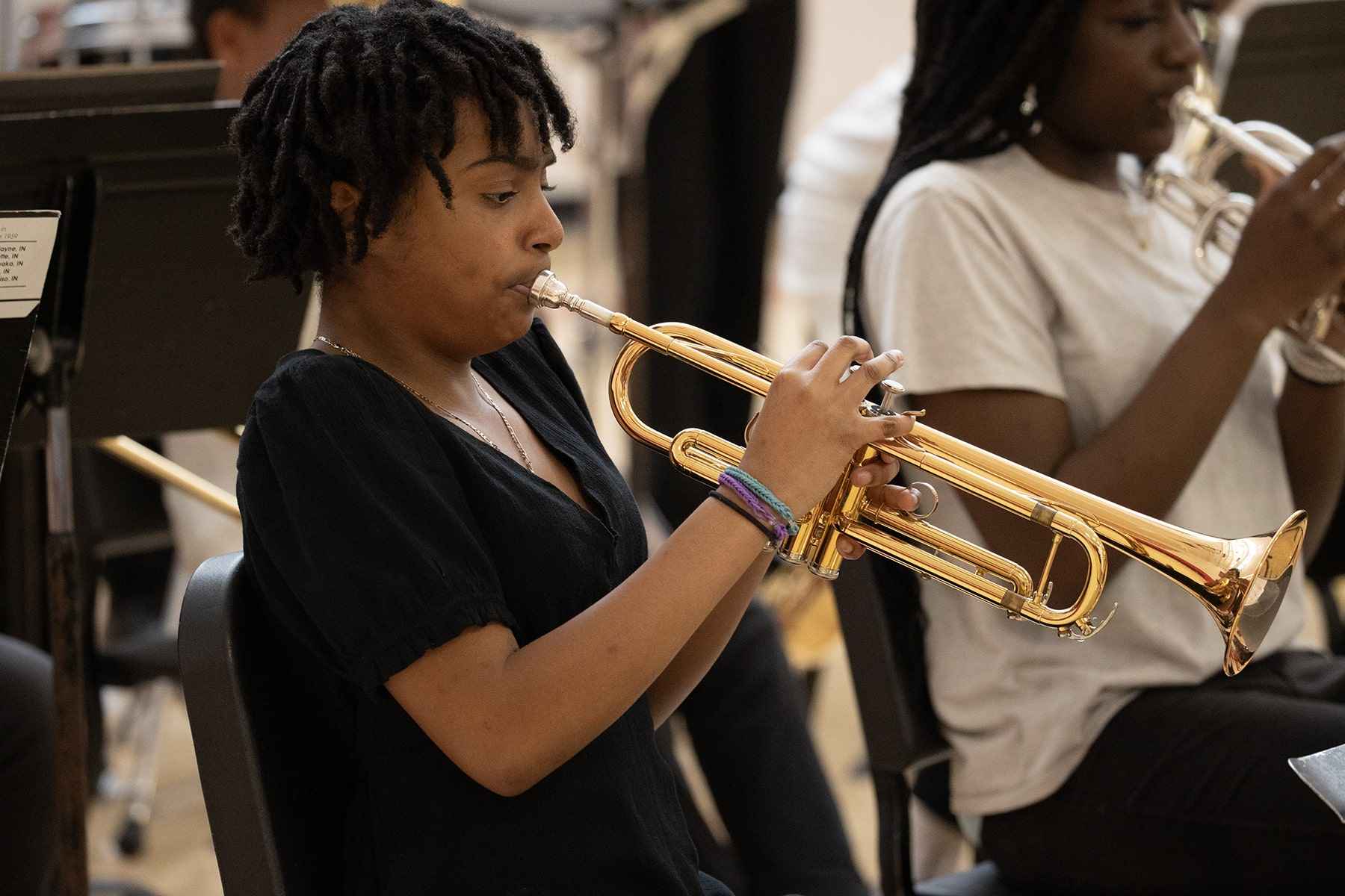 A female musician passionately playing the trumpet as part of a band performance.