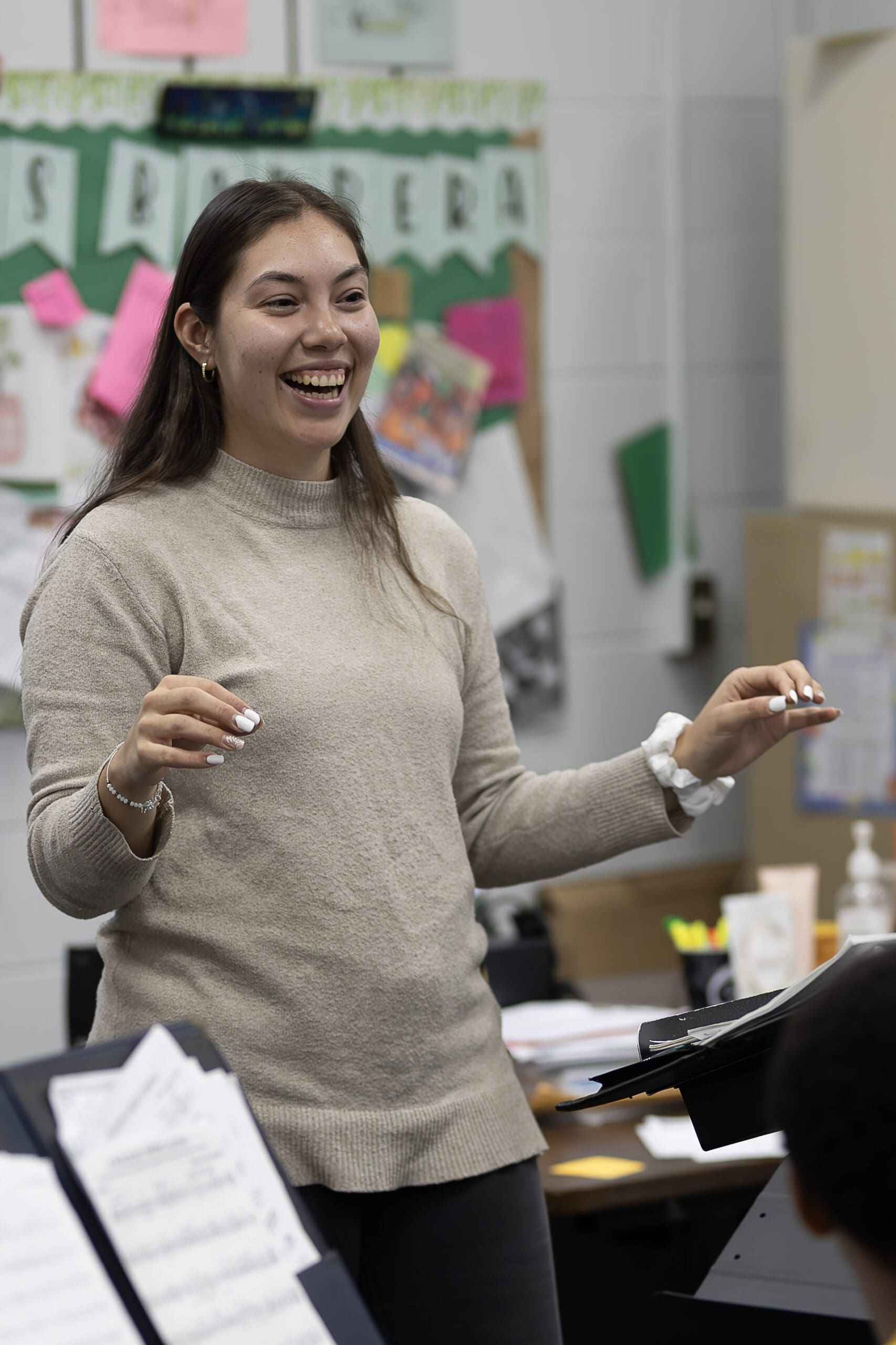 In a classroom, a woman speaks into the band room, addressing students and leading an interactive learning session.